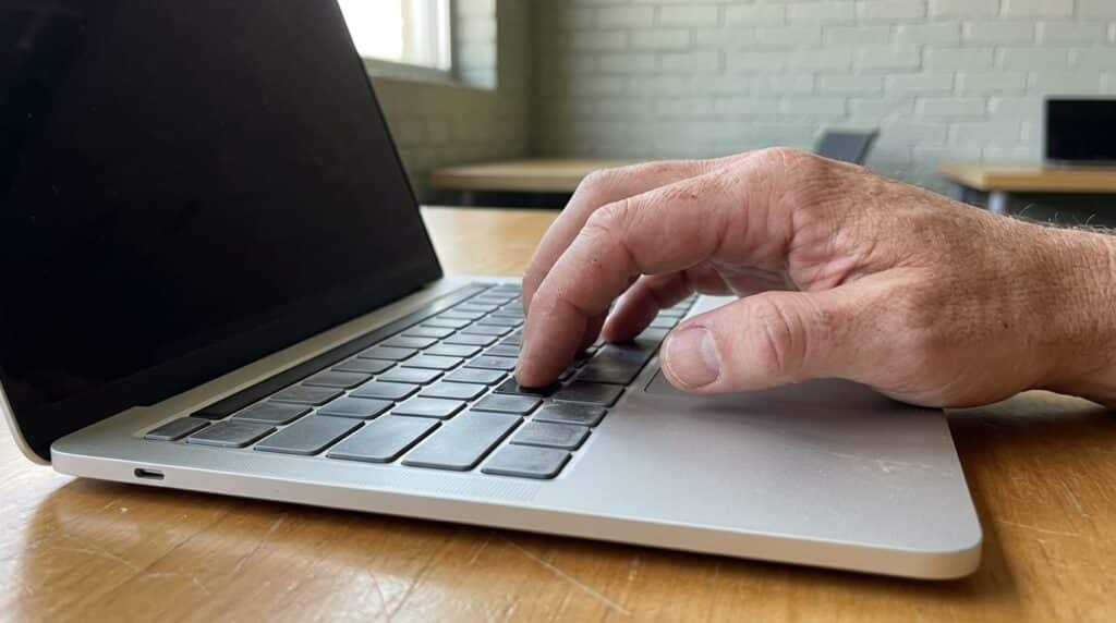 Business owner leaning toward laptop screen in a co-working space, reacting with concern to AI-generated text about their company.