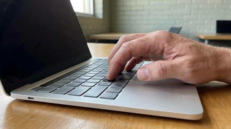 Business owner leaning toward laptop screen in a co-working space, reacting with concern to AI-generated text about their company.